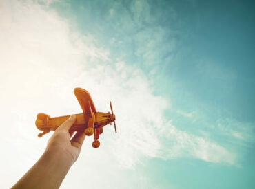 About Us - 2 Childhood inspiration - Hands of children holding a toy plane and have dreams wants to be a pilot - Vintage filter effect
